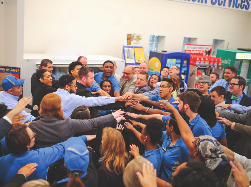 a photo of lots of people standing in a circle all putting their hands together in the iddle